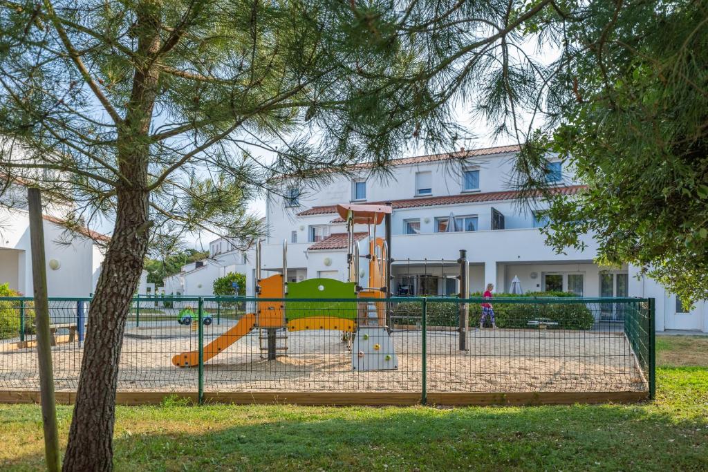 a playground with a slide in front of a building at Résidence Prestige Odalys Le Domaine des Pins in Noirmoutier-en-l'lle