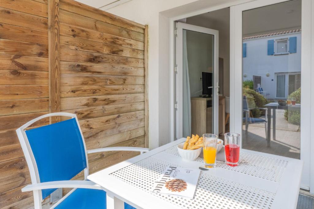 a white table and chairs with drinks on it at Résidence Prestige Odalys Le Domaine des Pins in Noirmoutier-en-l'lle