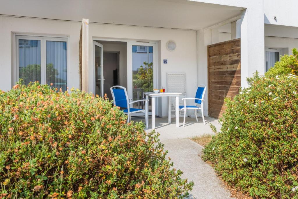 a patio with blue chairs and a table at Résidence Prestige Odalys Le Domaine des Pins in Noirmoutier-en-l'lle