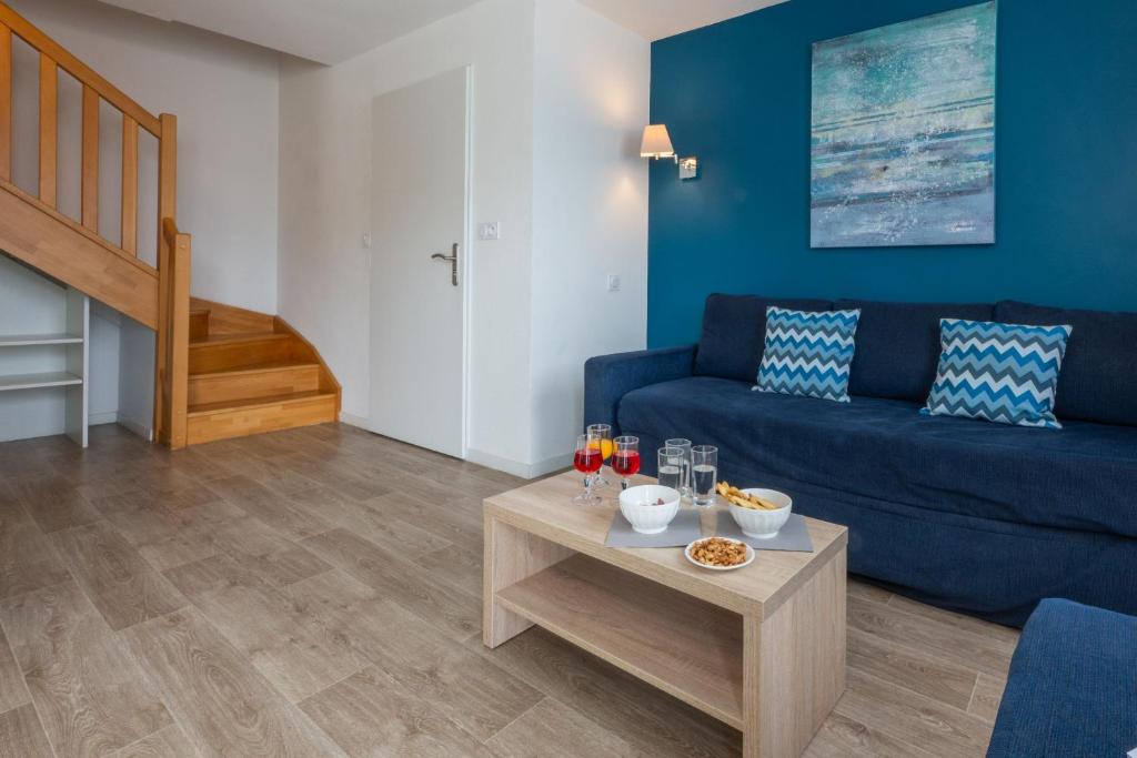 a living room with a blue couch and a table at Résidence Prestige Odalys Le Domaine des Pins in Noirmoutier-en-l'lle