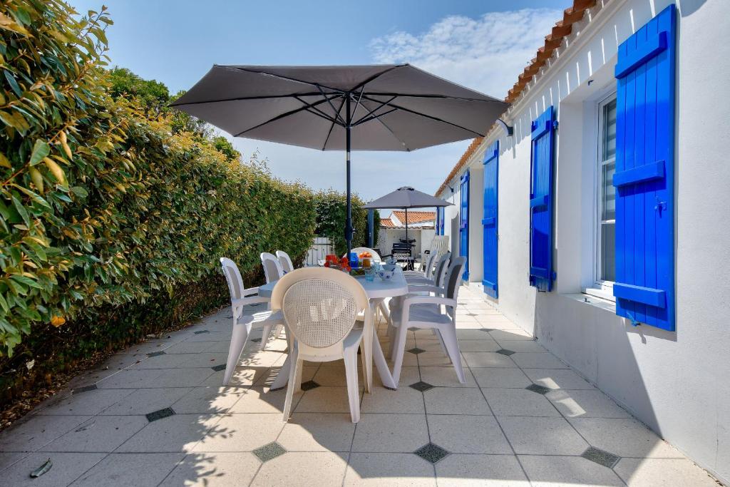 une table et des chaises avec un parasol sur une terrasse dans l'établissement 300 m du port - Jardin - Maison pour 6, à Noirmoutier-en-l'lle
