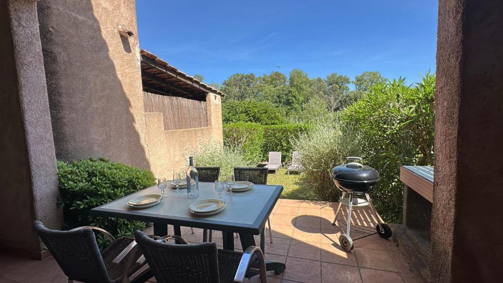 d'une terrasse avec un grill, une table et des chaises. dans l'établissement Mini-villa 2 pièces 4 couchages à 5 min de la plage de Pinarello, à Olmucciu