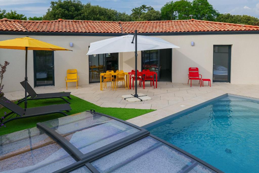 einen Pool mit einem Tisch, Stühlen und einem Sonnenschirm in der Unterkunft Villa des Hérondais avec piscine - idéal familles - 8 personnes in Jard-sur-Mer