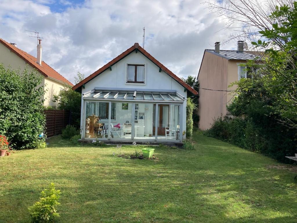 une petite maison avec une pelouse devant elle dans l'établissement Le calme entre Paris et Disney, à Villiers-sur-Marne