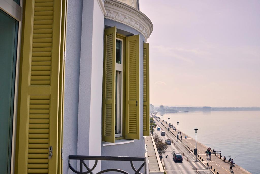 a building with yellow shuttered windows next to the water at ON Residence - Small Luxury Hotels of the World in Thessaloniki