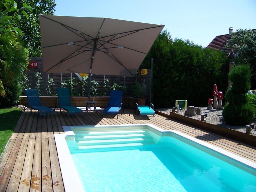 a swimming pool with an umbrella and chairs and a table at C&#39; 1 comble in Bischwihr