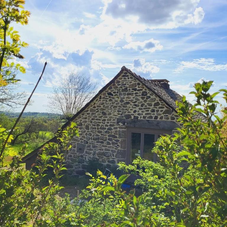 une ancienne maison en pierre avec des arbres devant elle dans l'établissement Le Mas de Rigoulac Gîte le Four, à Bouyssounouse