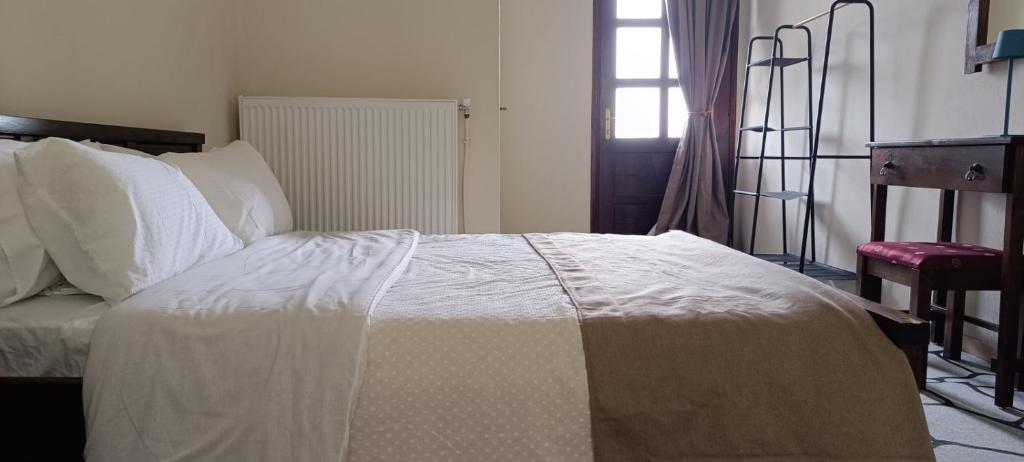 a bedroom with a bed with white sheets and a window at Panorama Elati in Elati Trikalon