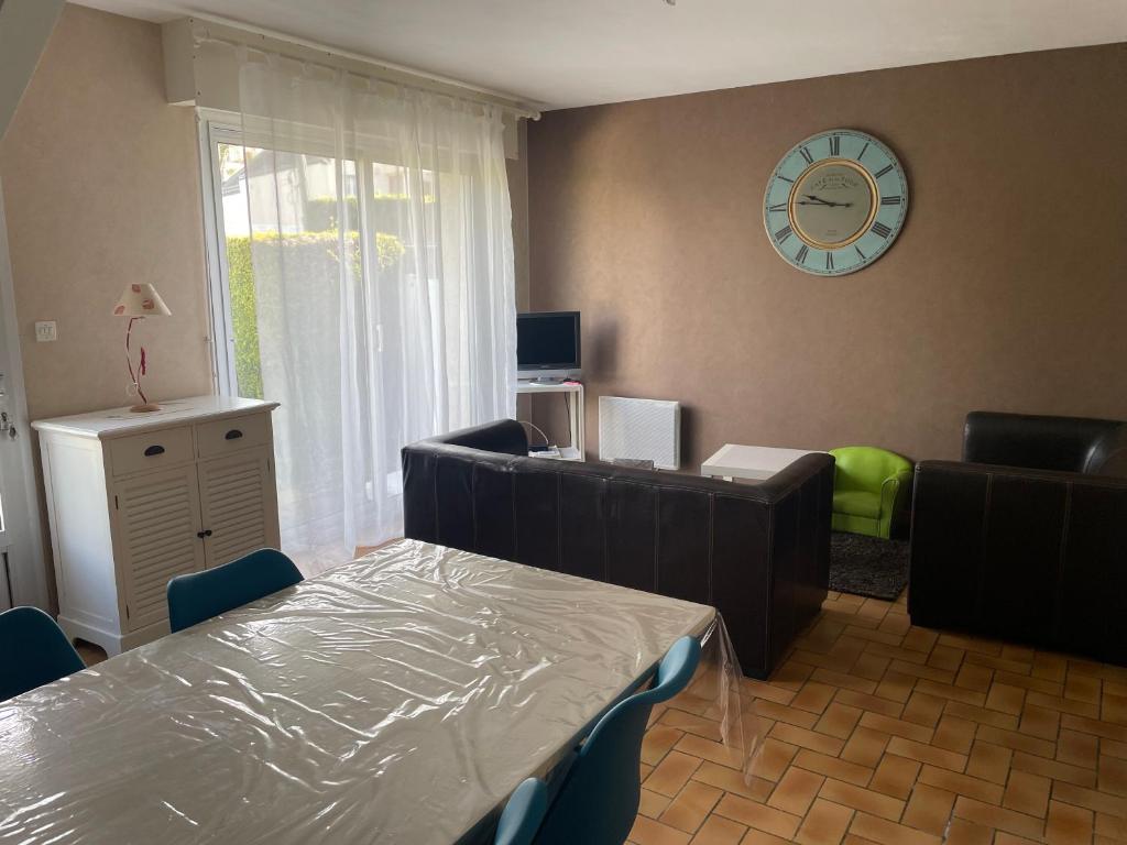 - un salon avec une table, des chaises et une horloge dans l'établissement Maison pieds dans l'eau Caroual, à Erquy