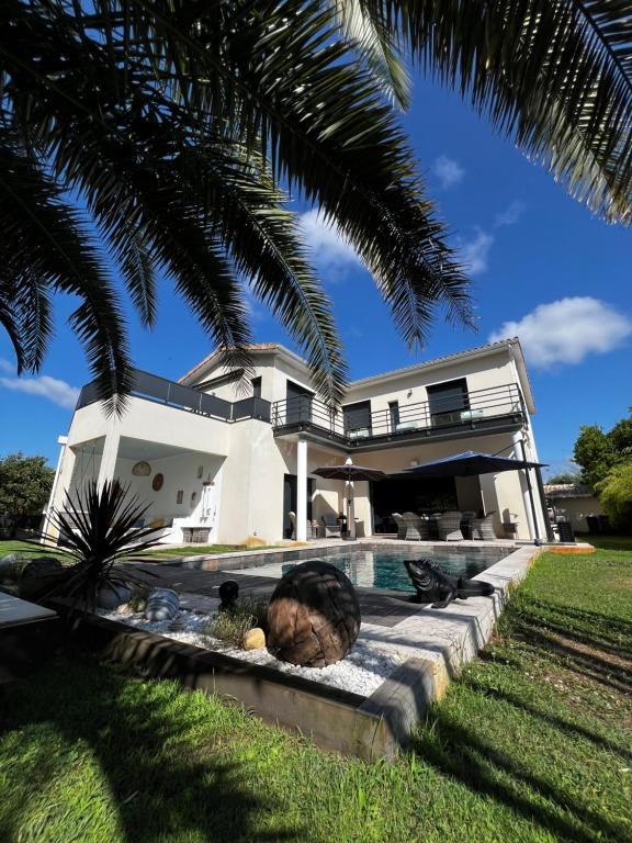 kot leżący na ziemi obok domu w obiekcie La Villa Des Trois Pins w mieście Andernos-les-Bains