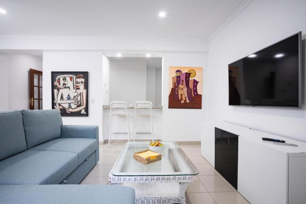 un salon avec un canapé et une télévision dans l'établissement Coral Canteras Playa - Frente al mar - Ideal parejas, familias o trabajo, à Las Palmas de Gran Canaria