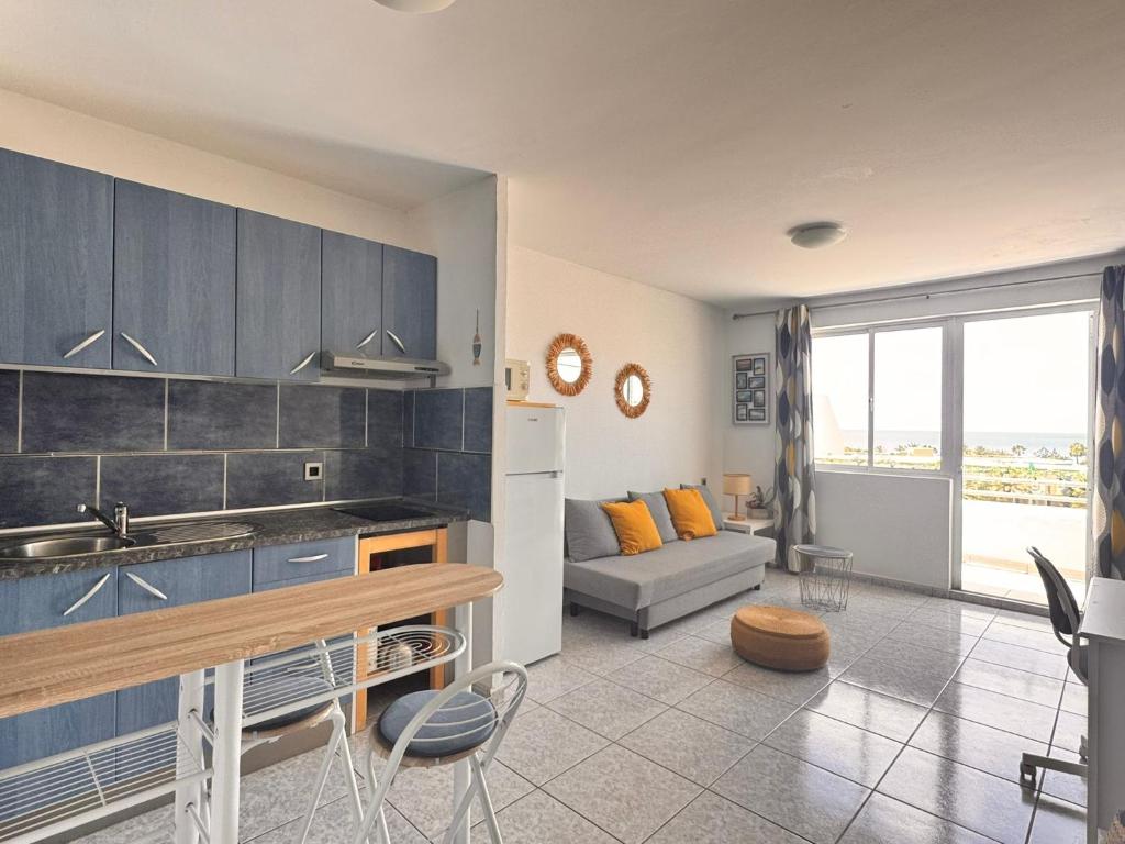 kuchnia i salon z kanapą i stołem w obiekcie Palm Garden Apartment w mieście Morro del Jable