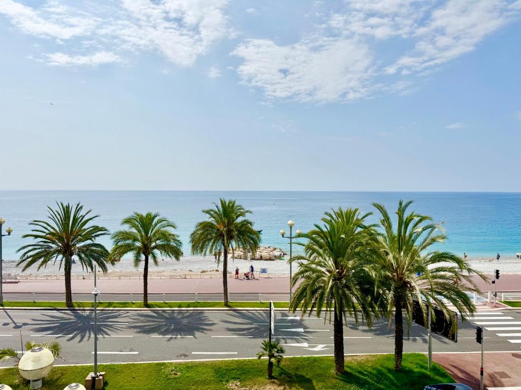 une vue sur une plage avec des palmiers et l'océan dans l'établissement Le Milord - Easy Home Booking, à Nice