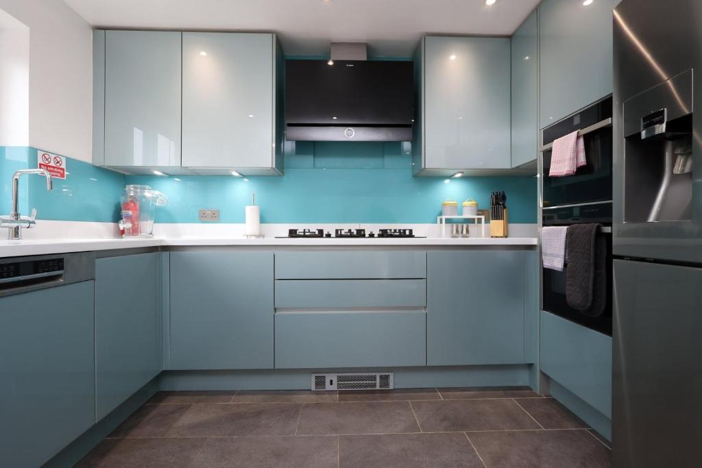 a kitchen with blue walls and white cabinets at Kites House Long Stays Sleep 8 Free Parking and WI-FI in Bristol