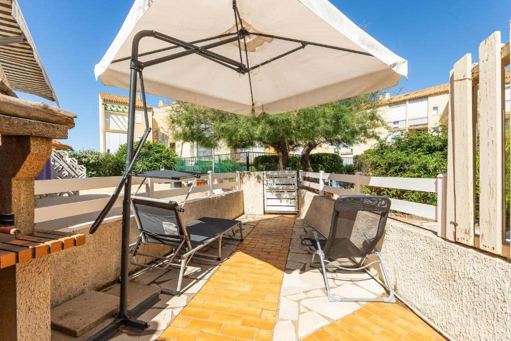 un patio avec deux chaises et un parasol dans l'établissement Le Santa-Marina - proche plage, à Fleury