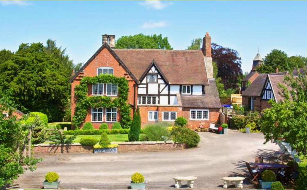 a large red brick house with a driveway at The Manor House in Marston Montgomery