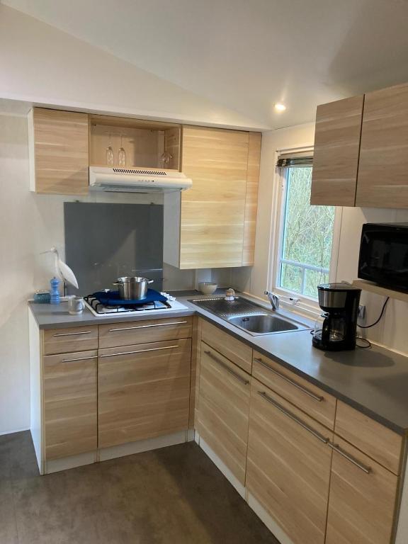 une cuisine avec des armoires en bois, un évier et une cuisinière dans l'établissement La petite maison - Camiers, à Camiers