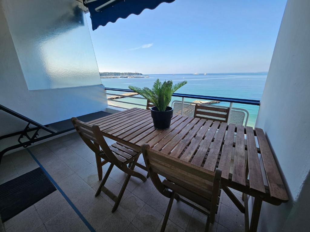 une table en bois avec des chaises et une plante en pot sur un balcon dans l'établissement Juan les Pins Front de Mer 2P parking Colombier, à Antibes