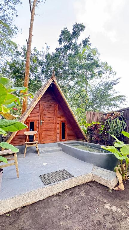 a small wooden cabin with a thatched roof at Triangle House and hot spring in Kintamani