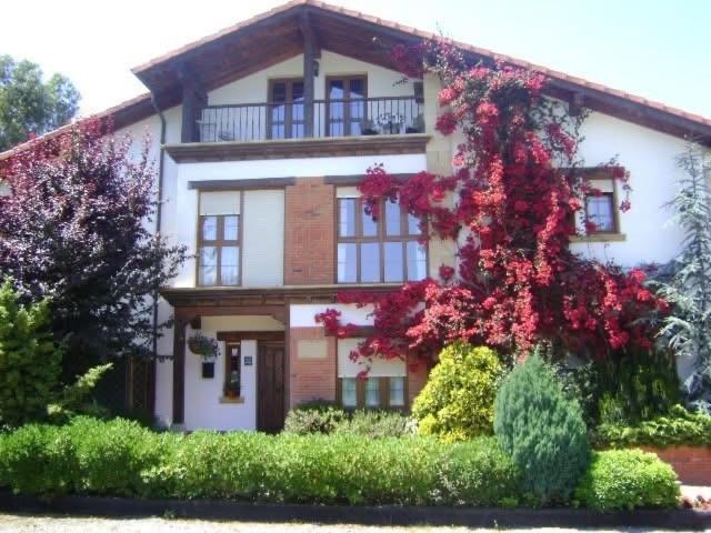 dom z czerwonymi kwiatami na boku w obiekcie Apartamentos Dos Robles w mieście Somo