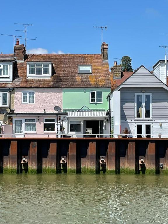 a dock in front of a house next to water at Dove Cottage is a Central, Riverside, Charming Victorian Cottage in Arundel