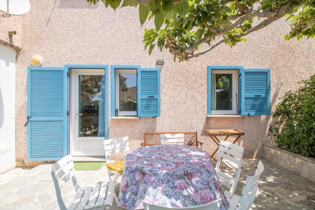 Una mesa y sillas frente a una casa con ventanas azules. en T4 Marine Sant'ambroggio, en Lumio