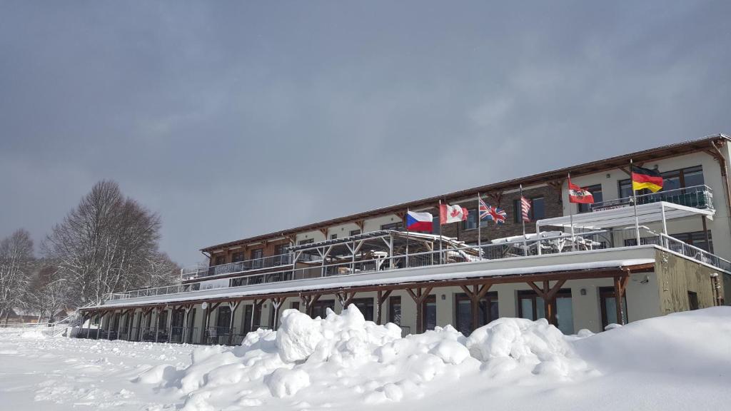 a building with snow in front of it at Aparthotel Rezidence Club Canada Lipno in Lipno nad Vltavou