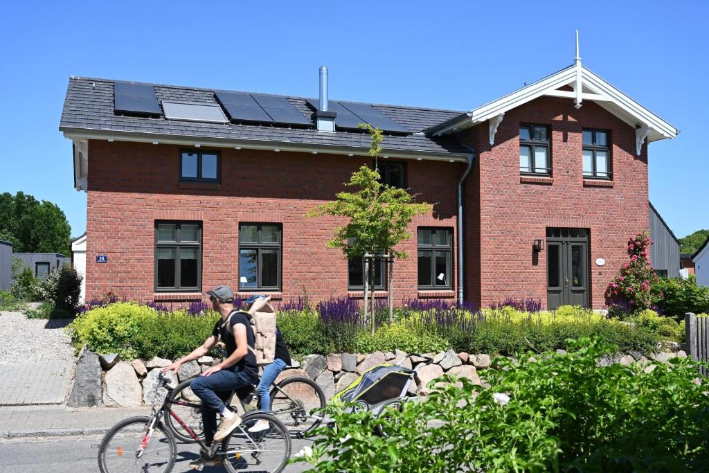 two people riding bikes in front of a brick house at Elsas Enkel - Ferienwohnung Gesa in Waabs