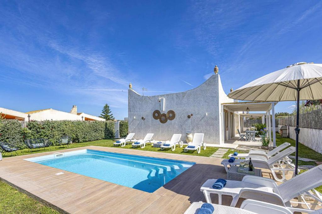 - une piscine avec des chaises blanches et un parasol dans l'établissement Villa Rosso Blu by Villa Plus, à Santa Maria Del Focallo