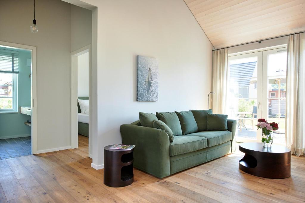 a living room with a green couch and a table at Elsas Enkel - Ferienwohnung Meta in Waabs