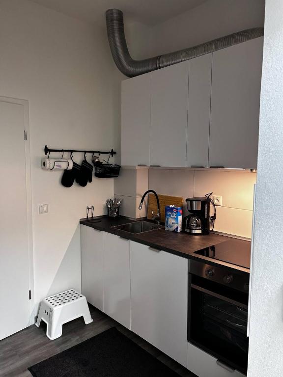 Una cocina con gabinetes blancos y un fregadero. en FeWo Vermietung Plauen, en Plauen