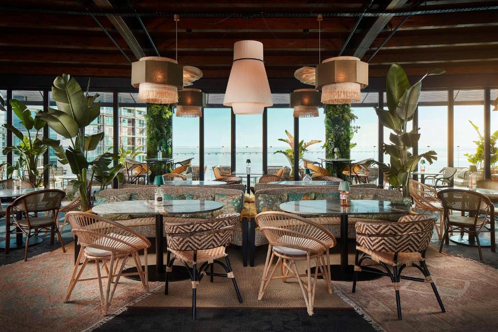 um restaurante com mesas e cadeiras com vista para o oceano em Tivoli Oriente Lisboa Hotel em Lisboa