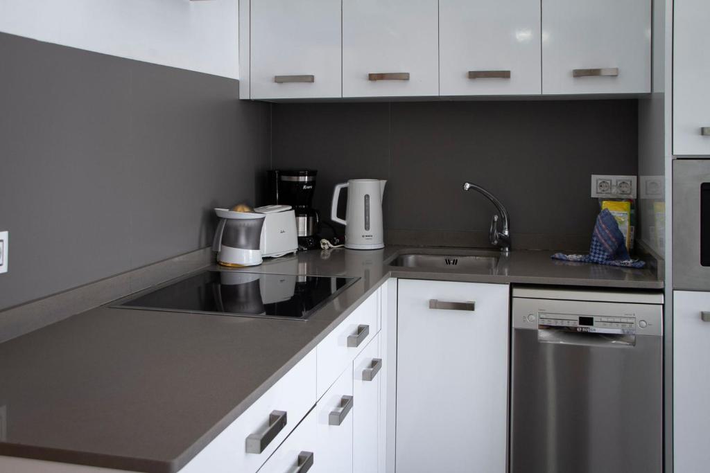 a kitchen with white cabinets and a stainless steel sink at Holiday Club Puerto Calma in Puerto Rico de Gran Canaria