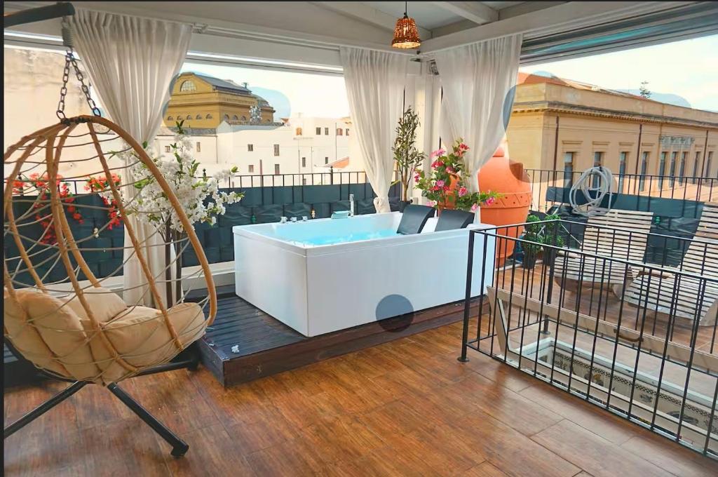 a room with a tub and a chair on a balcony at Teatro Massimo Terrace relax suite in Palermo