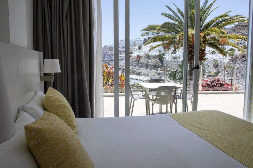 a bedroom with a bed and a balcony with a table at Holiday Club Puerto Calma in Puerto Rico de Gran Canaria