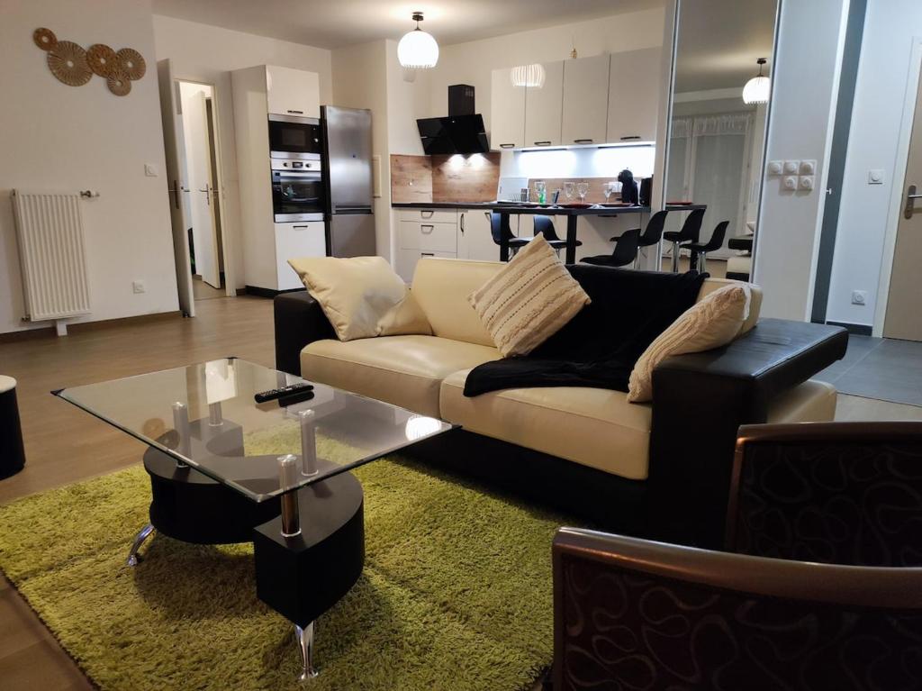 a living room with a couch and a glass table at L'AuthentiCité, jardin et parking au centre-ville in Dijon