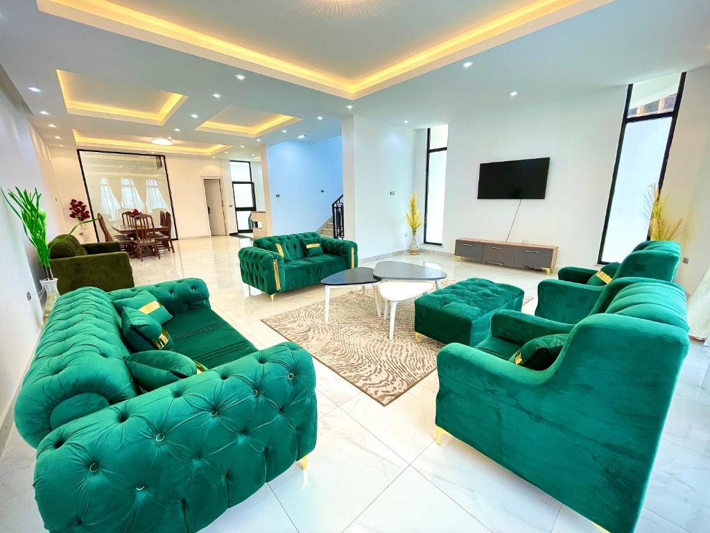 un soggiorno con divani verdi e TV di Luxurious & Spacious Mega Home! ad Addis Abeba