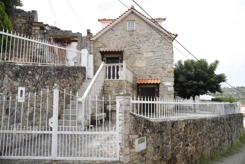 uma antiga casa de pedra com uma cerca branca em Stone House em Salzedas