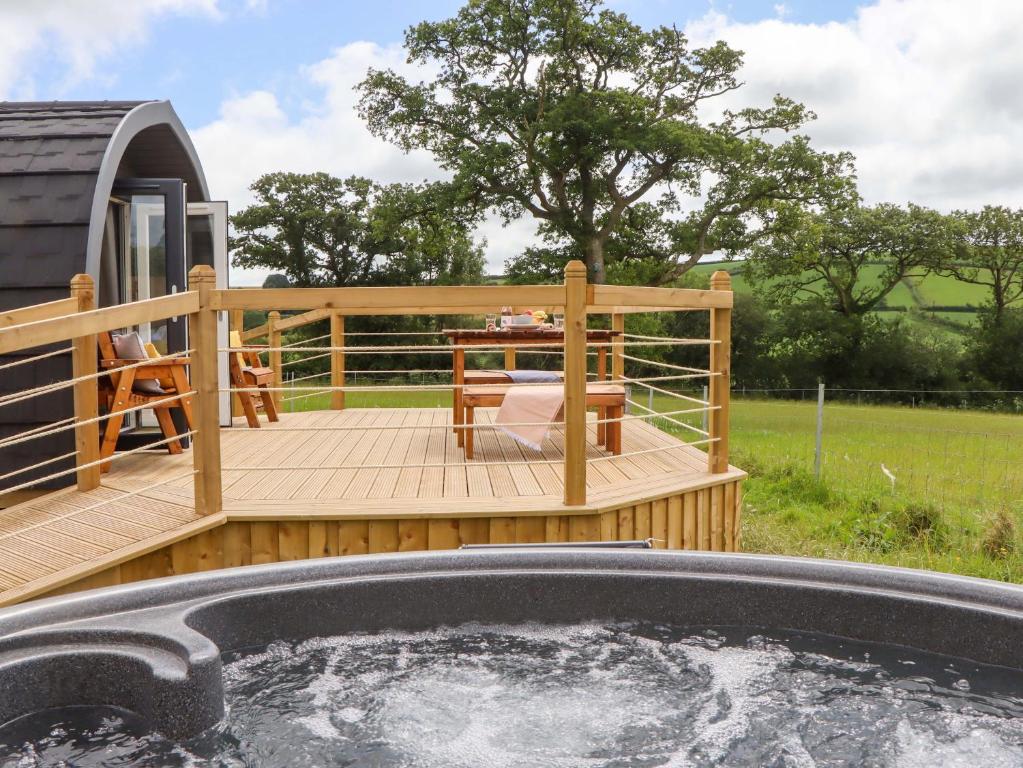 a deck with a hot tub and a table at Under Oak Pod in Totnes