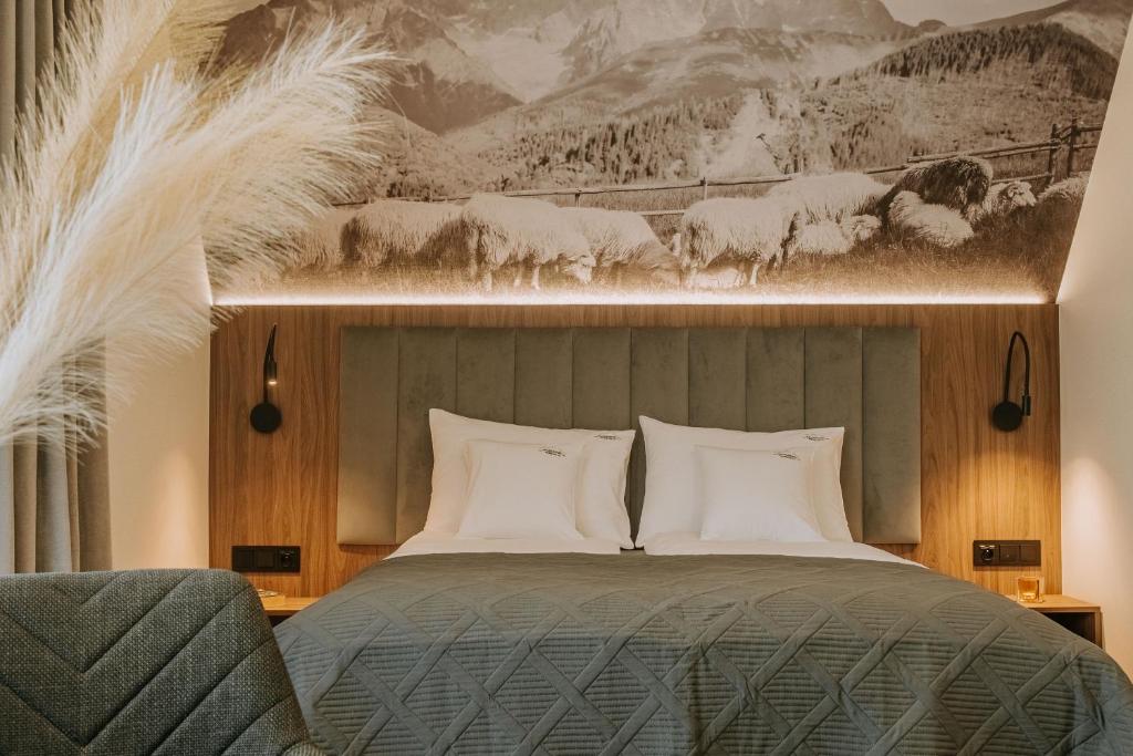 a bedroom with a bed and a painting of sheep at Willa Bachledzki Wierch 12 in Zakopane