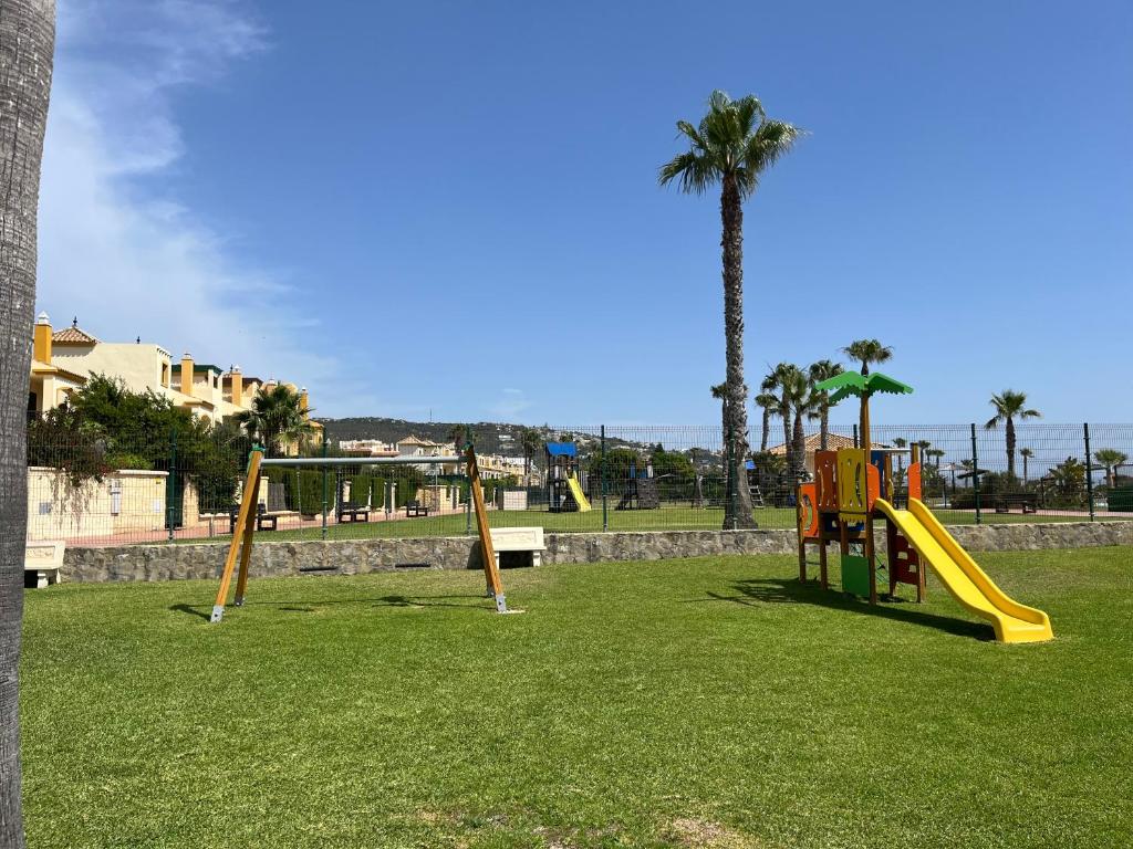 plac zabaw ze zjeżdżalnią w parku z palmą w obiekcie Ático duplex con vistas al mar en Zahara de los Atunes w mieście Zahara de los Atunes