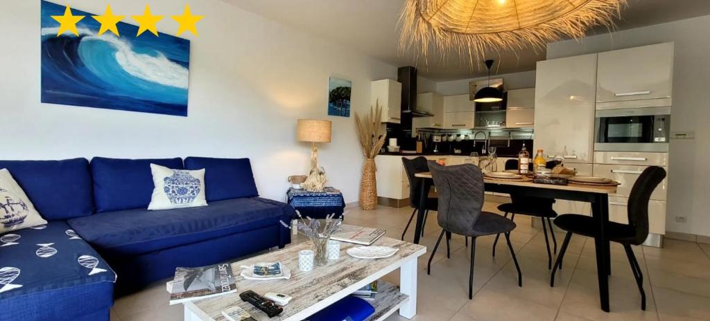 un salon avec un canapé bleu et une cuisine dans l'établissement Apartment Blue Riviera - am Strand mit Meerblick und Pool by Riviera HomeLife, à Saint-Raphaël