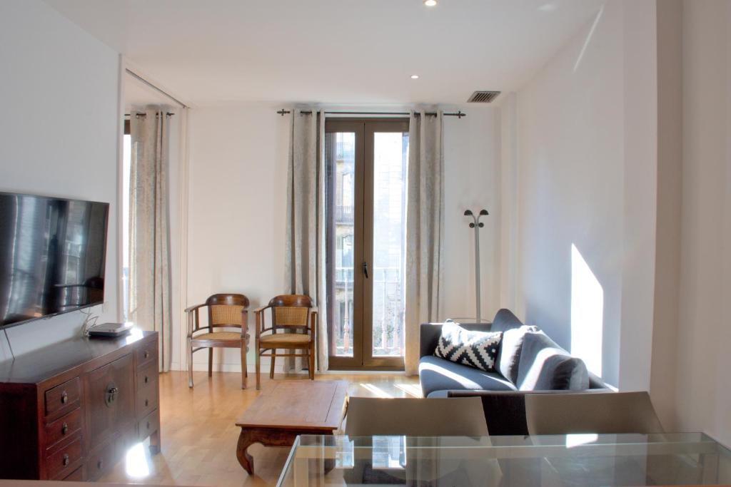 a living room with a couch and a tv at SWEET BCN Rambla 48 in Barcelona