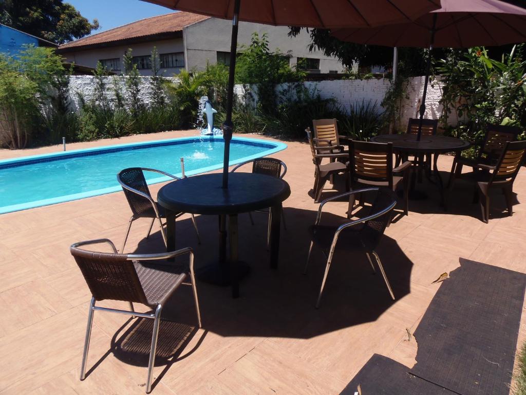 a table and chairs with an umbrella next to a pool at Meliza's Garden in Foz do Iguaçu