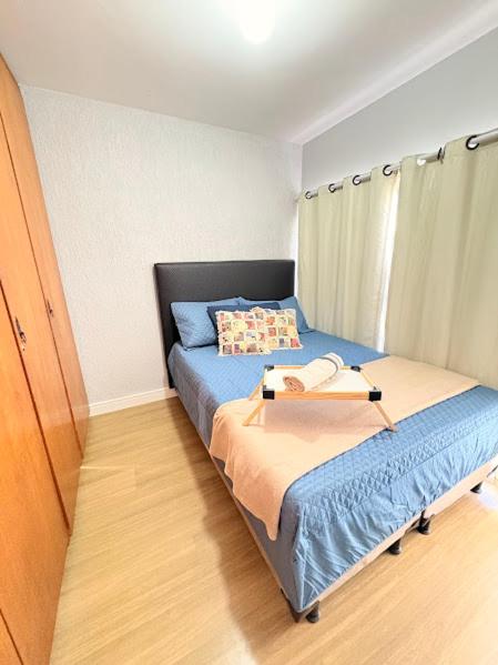 a small bedroom with a bed with a blue bedspread at Apê Refúgio Urbano in Brasília