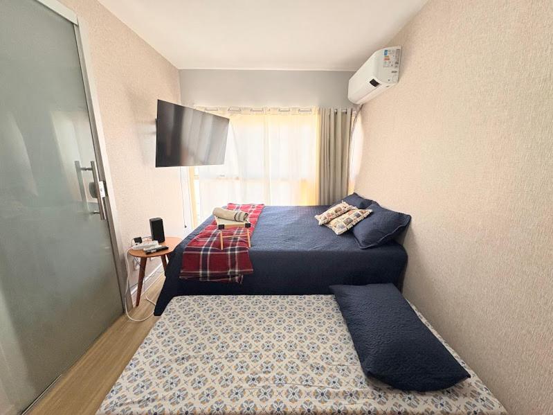 a hotel room with two beds and a tv at Apê Refúgio Urbano in Brasilia