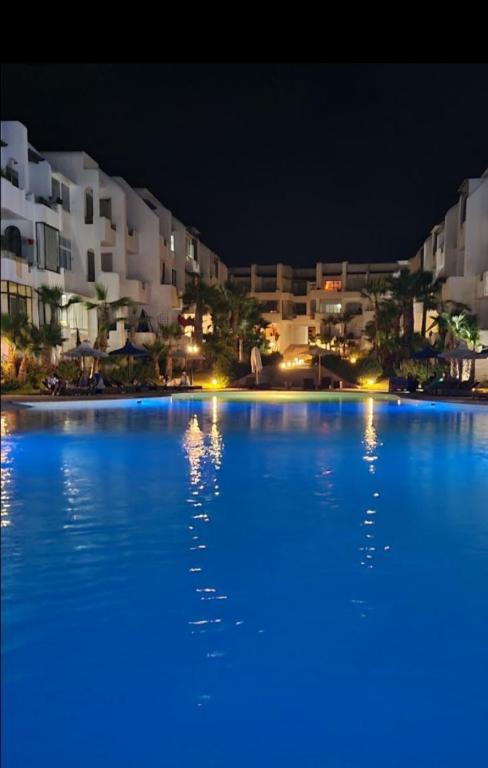 a large blue swimming pool at night with buildings at Mansouria beach resort in Mohammedia