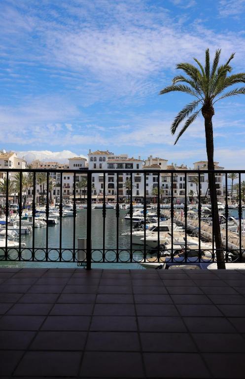 a view of a harbor with a palm tree and buildings at Puerto Duquesa fancy condo overlooking Marina in Manilva