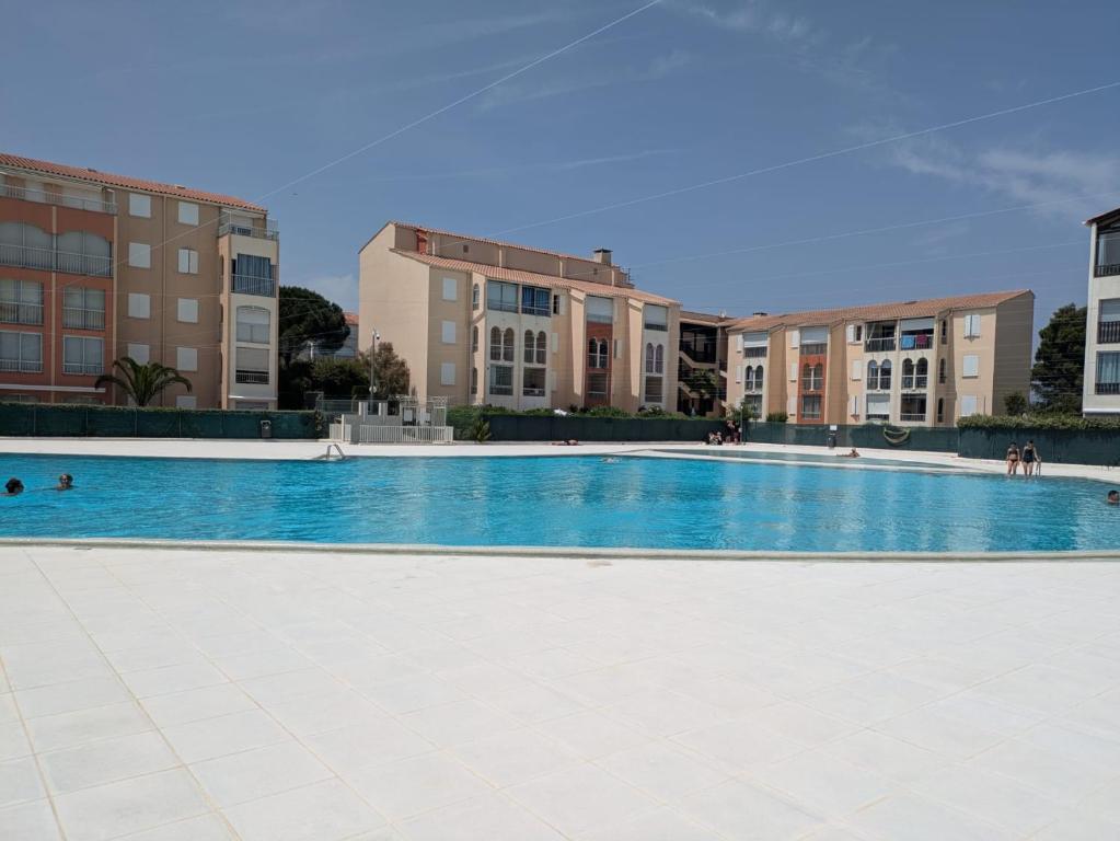une piscine vide avec des bâtiments en arrière-plan dans l'établissement Bel Appartement T2 - Résidence Lagon Bleu - Piscine, à Fréjus