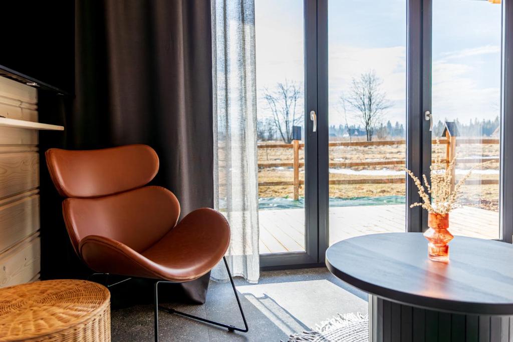 a room with a chair and a table and a window at RentPlanet - Wierzchołki - Domki 8-osobowe in Chochołów
